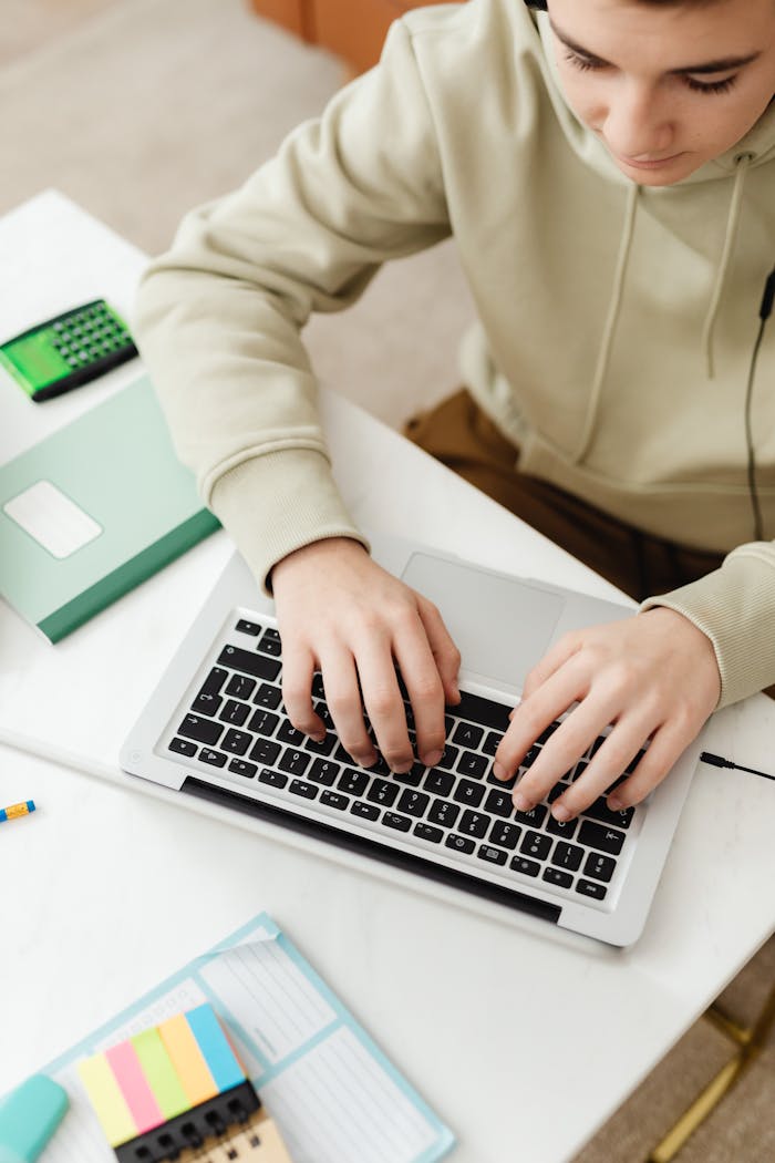 The Art of Drawing Readers In: Your attractive post title goes here Teenager in hoodie using a laptop for online education with study materials around.